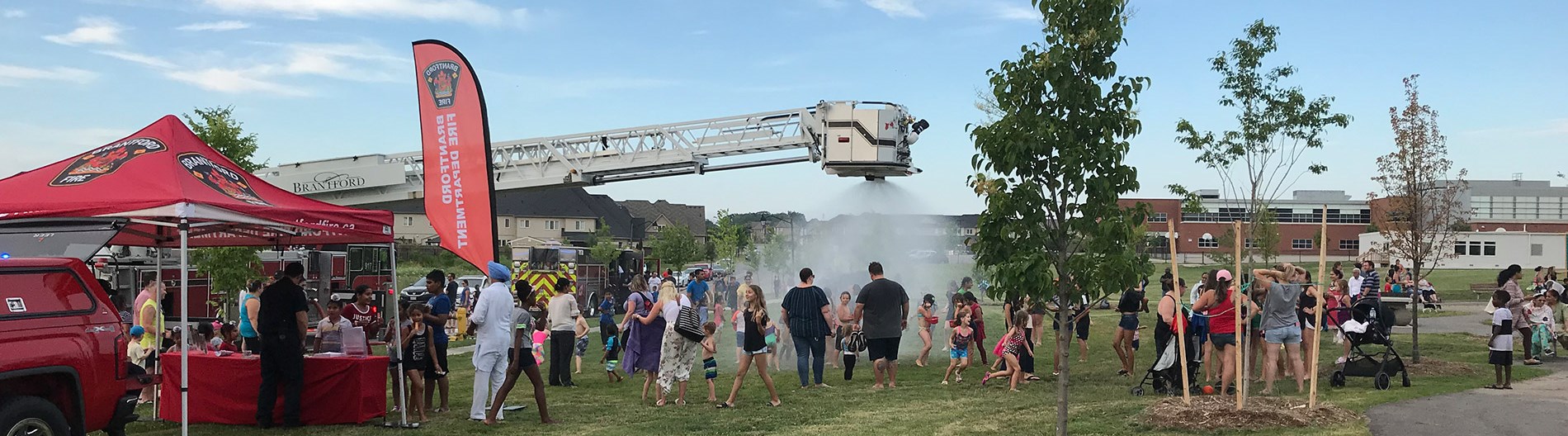Fire truck sprinkler running with kids underneath water
