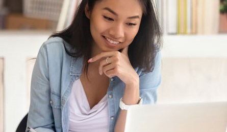 lady viewing laptop screen and writing information down