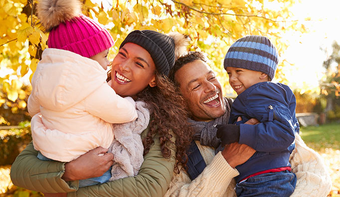 Two parents and their two children laughing in a park