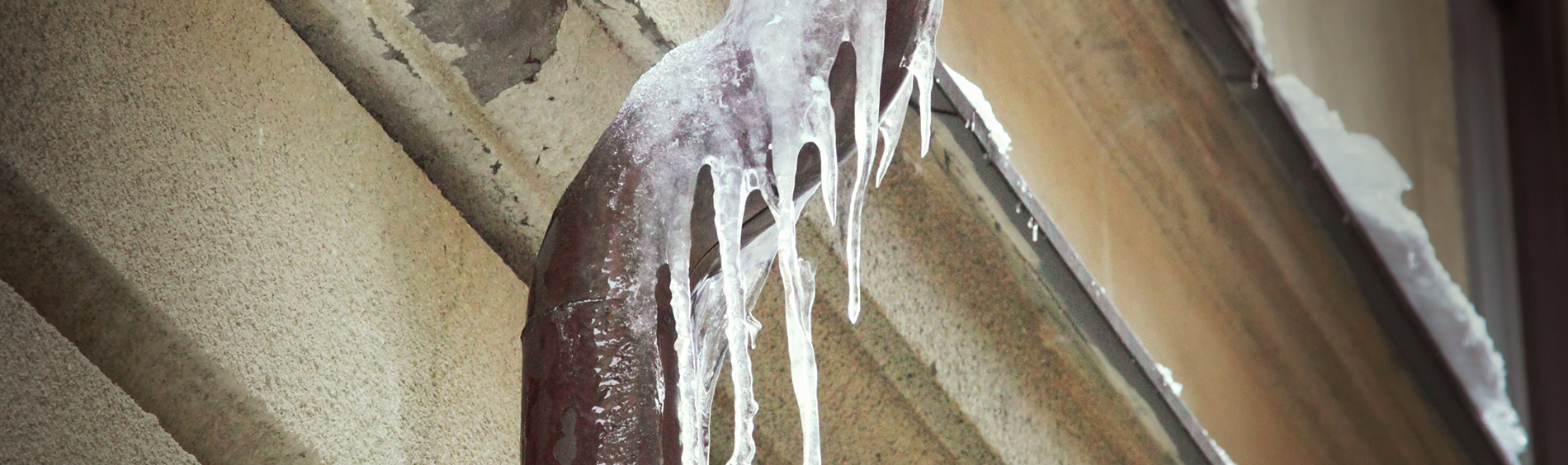 frozen pipe with icicle at side of home