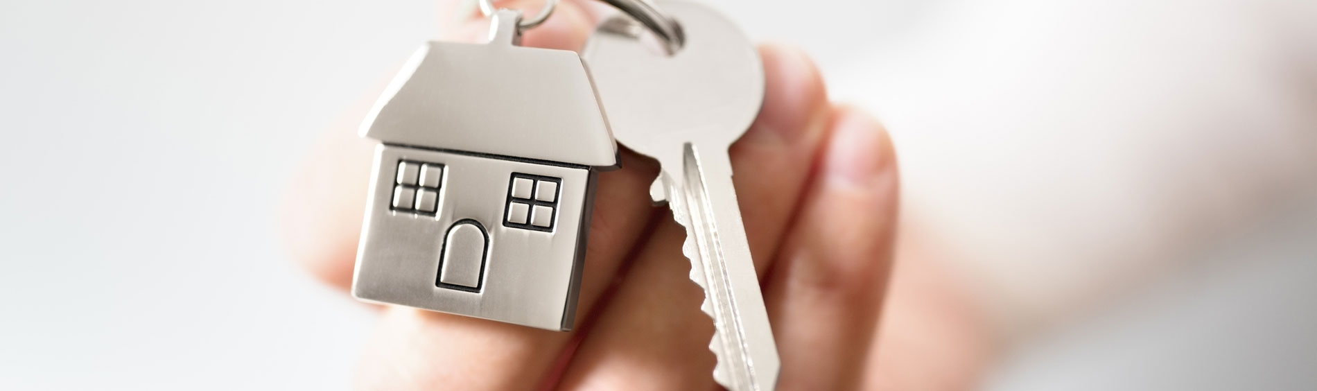 A hand holds a set of keys with a house keychain