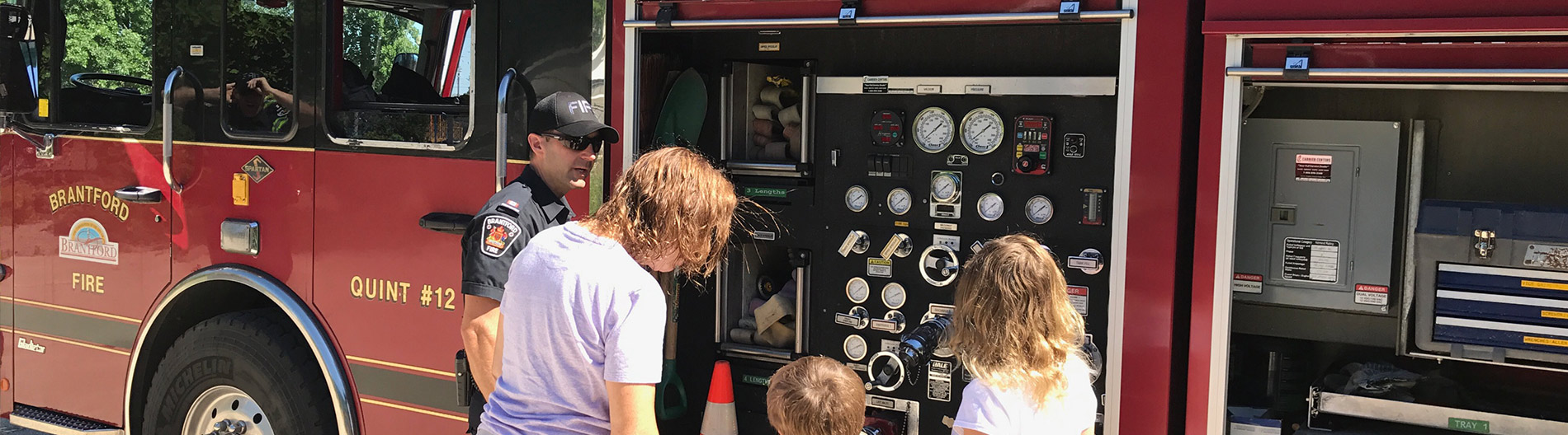 Firefighter with community members in front of a fire truck