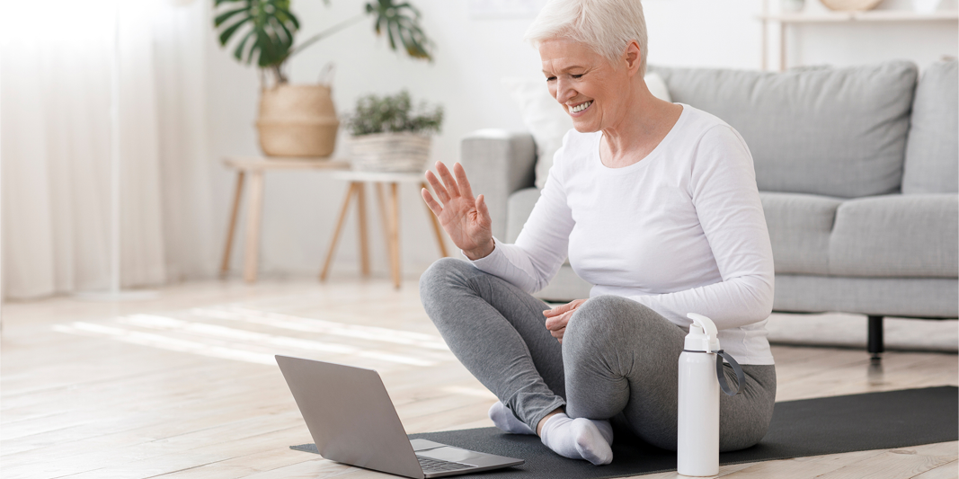 Older woman exercising with a laptop in front of her