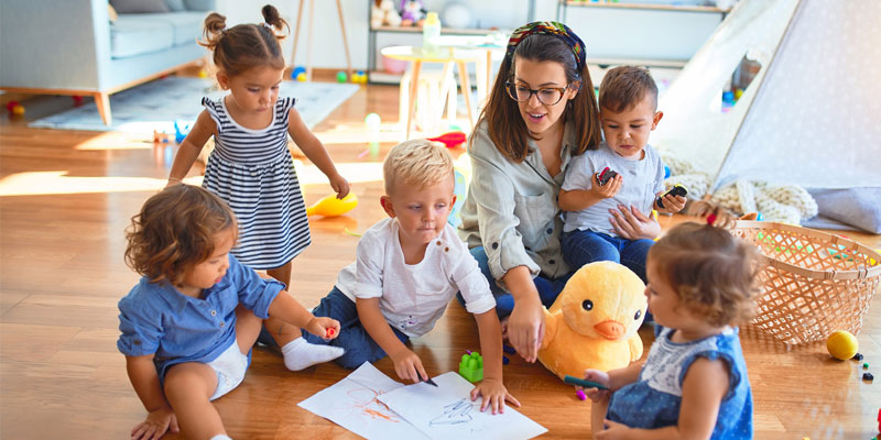 Early Childhood Educator sits with children