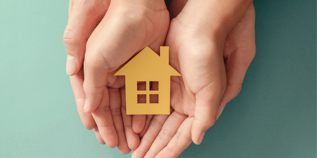 Hands holding a cut out of a yellow house