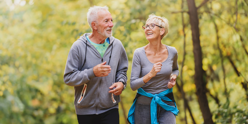 Senior couple walking with trees in the background