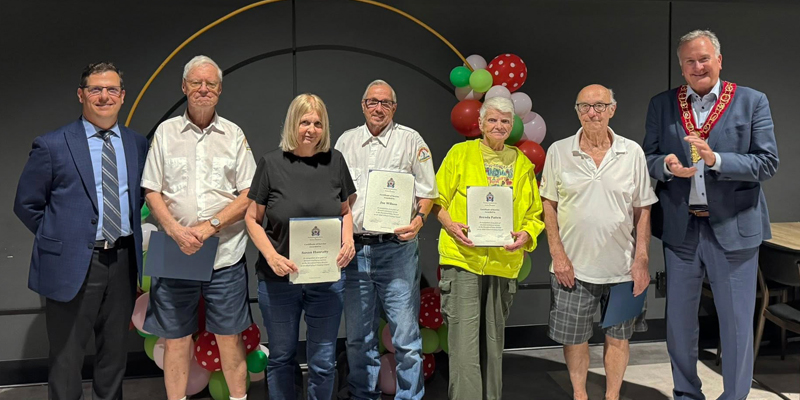 Five Adult School Crossing Guards stand with Mayor Davis holding their years of service recognition papers