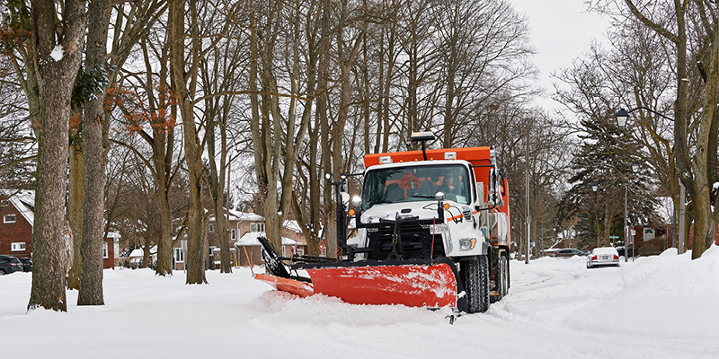 Snow plow removing snow on a residential street