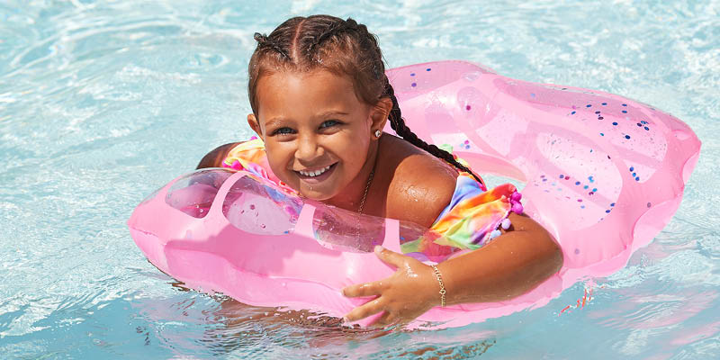 Young girl in a swimming pool in a pink inner tube