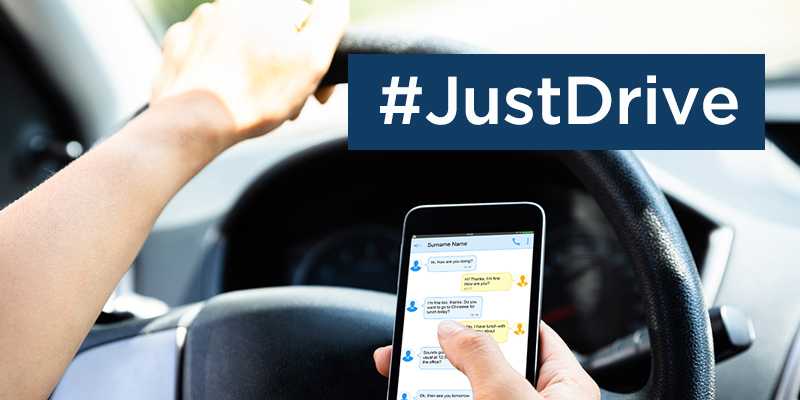 Individual texting while driving with text overlay that says "Just Drive"