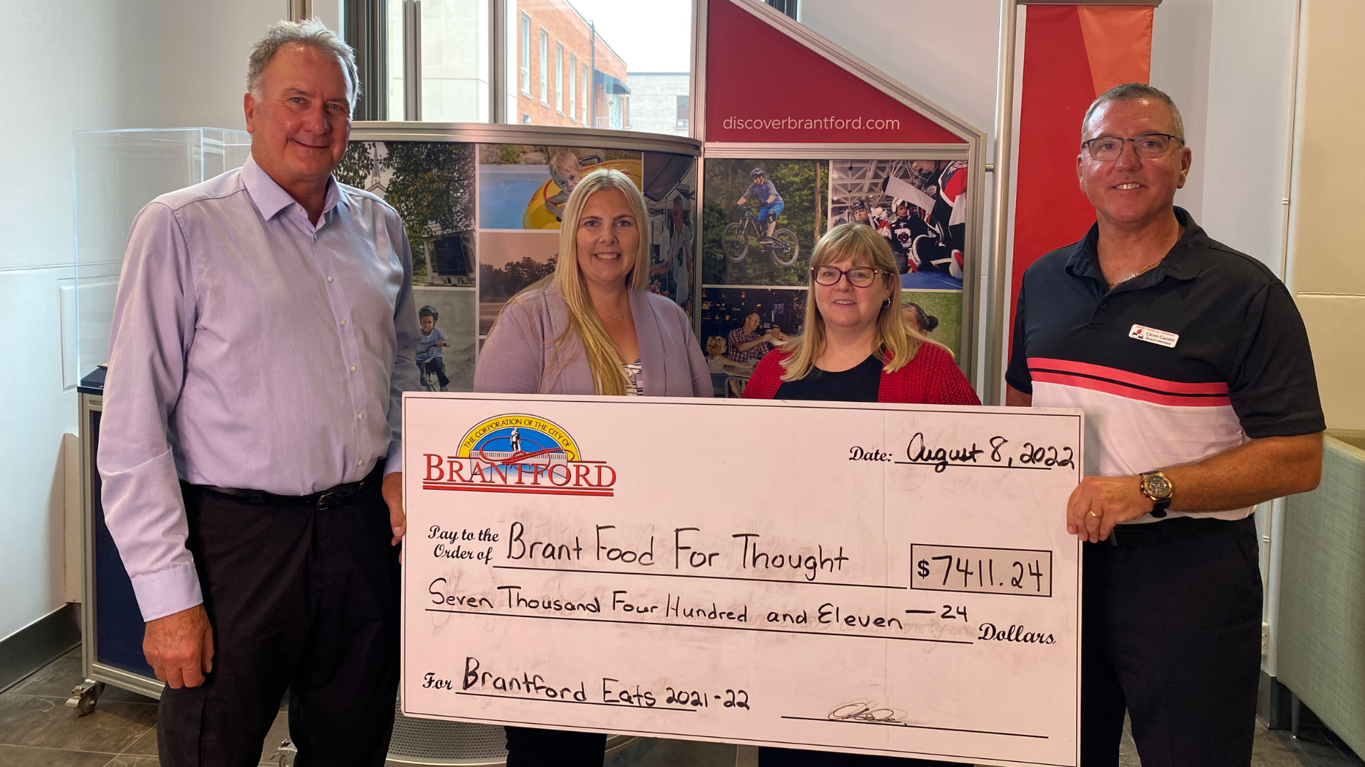 Mayor Kevin Davis presents a cheque for $7,411.24 to Brant Food for Thought for the total proceeds raised from Brantford Eats Local booklet sales.
