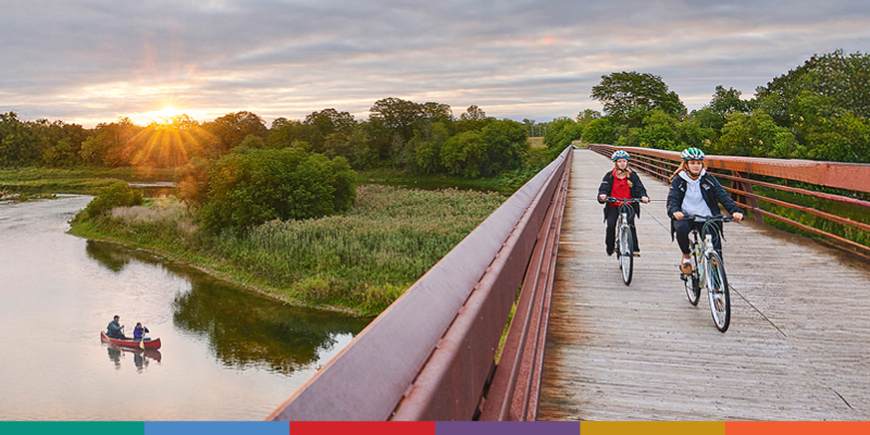 Two people cycling on a bridge over the Grand River