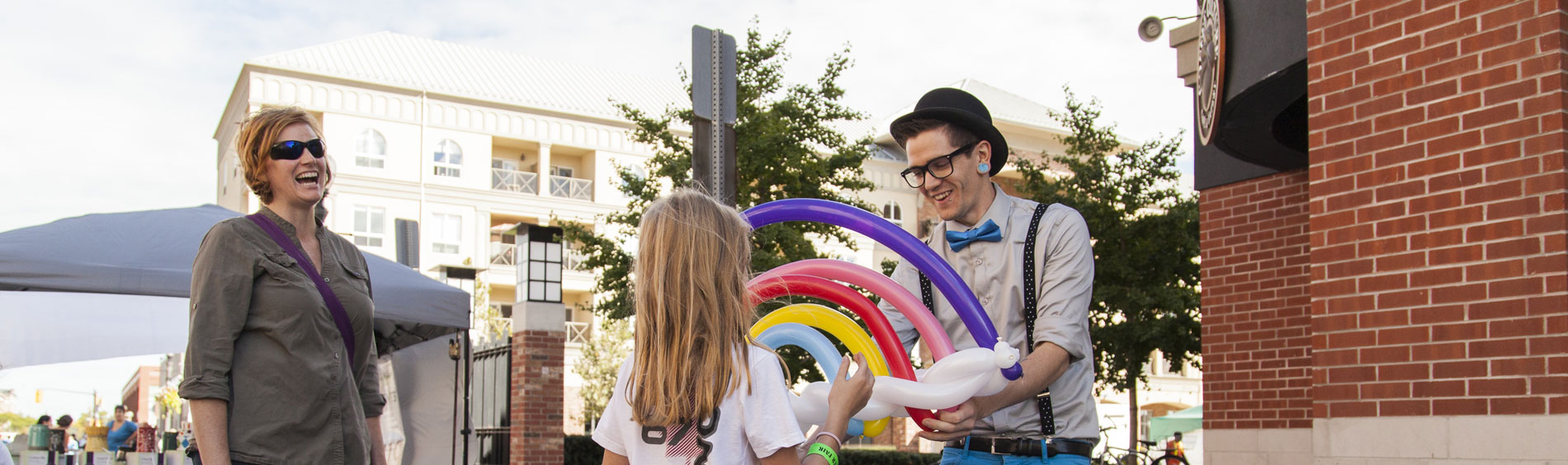 Busker creating balloon art for a child at Harmony Square