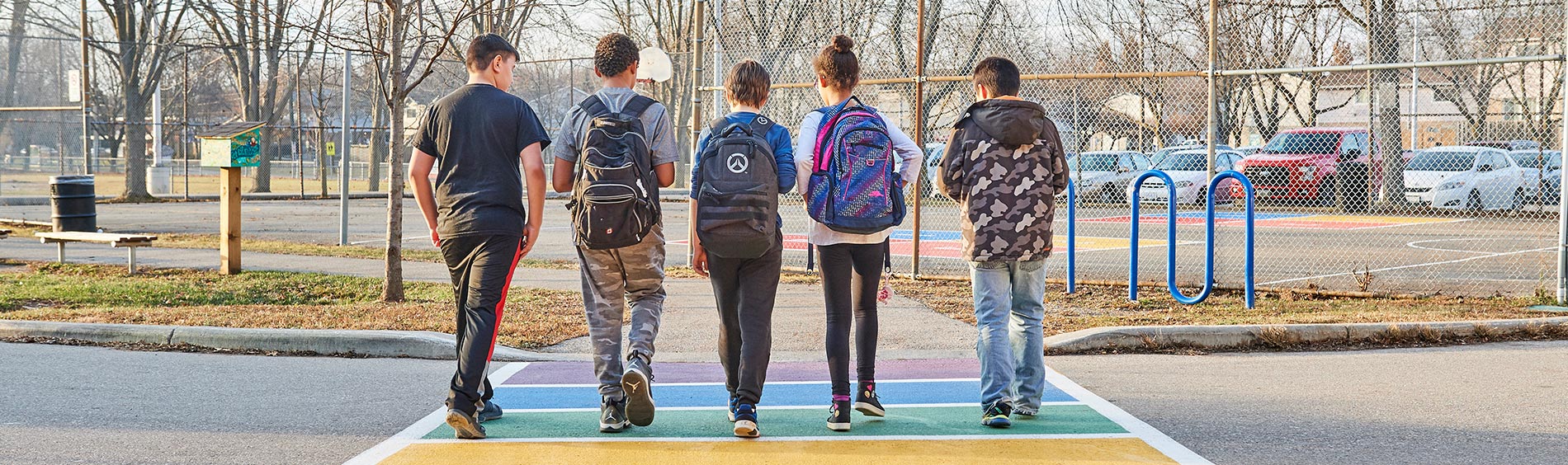 Kids walking across a rainbow cross walk