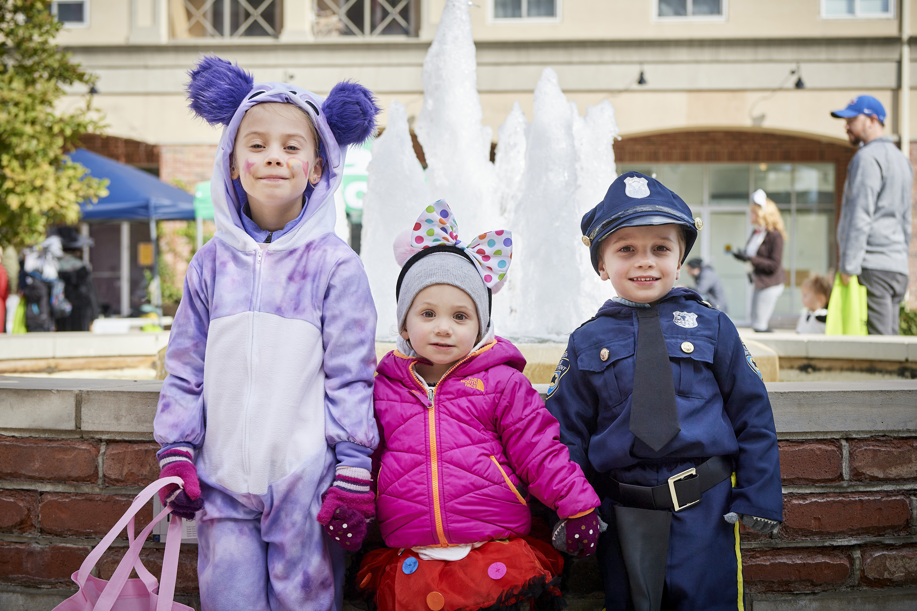 Kids dressed up for Halloween in Harmony Square holding treat bags
