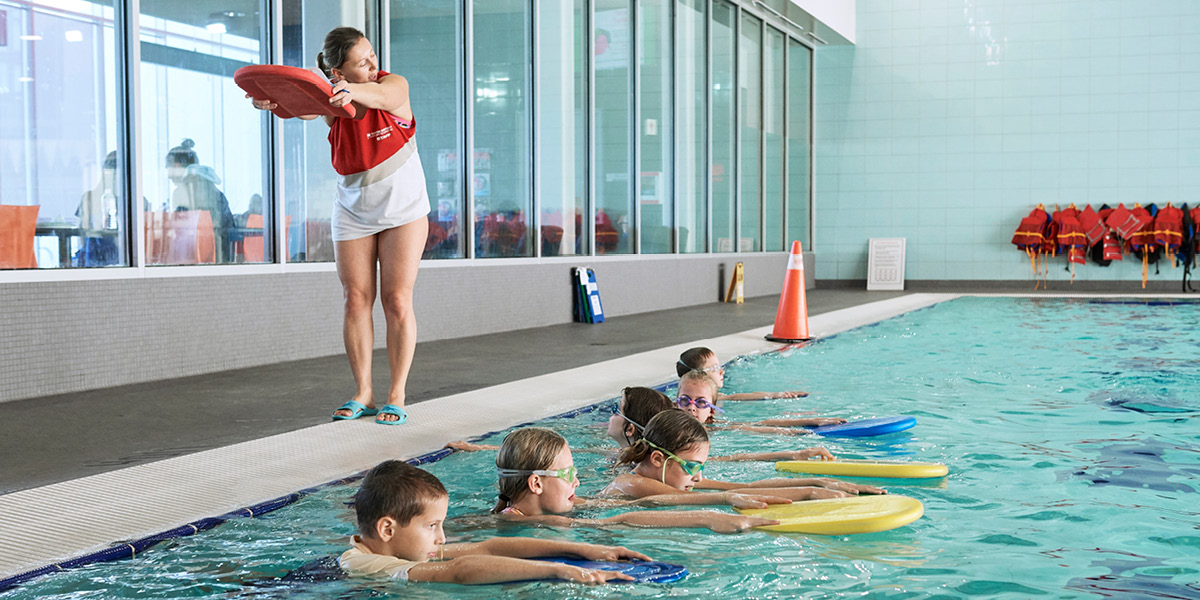 A female lifeguard teaching a class holding a flutter board