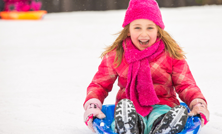 Little girl sledding down a hill