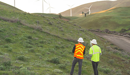 workers assessing hill with windmills