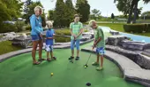 An adult and two children playing mini golf
