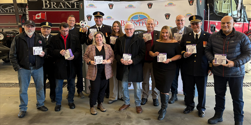 Various members of City of Brantford Council, Brantford Fire and Fire Marshal's Public Safety Council pose with smoke and carbon monoxide alarms in front of a fire truck