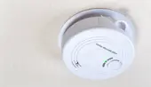 An installed carbon monoxide alarm on a white ceiling